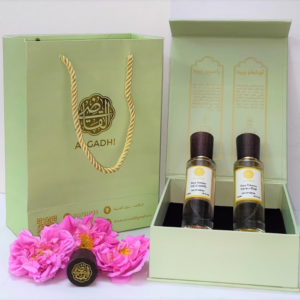 AlGadhi gift set featuring two luxurious perfumes, Tobacco Rose and Jasmine Rose, elegantly presented in a premium green box with a branded shopping bag and fresh roses