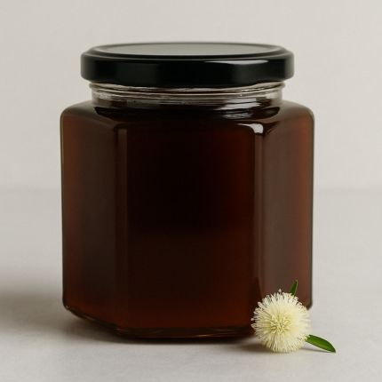 برطمان عسل سمرة بلدي سعودي طبيعي100% خام نقي بلون كهرماني داكن، بجانبه زهرة شجرة السمر، يظهر جودة عسل السمرة الأصيل.